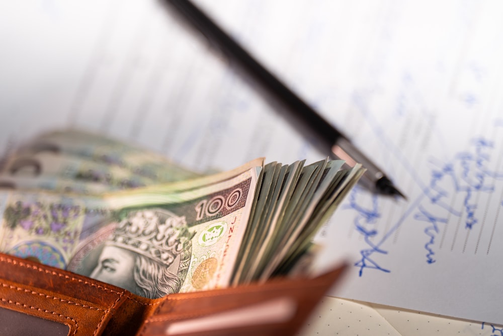 A stack of Polish banknotes and a black pen rest on a paper document