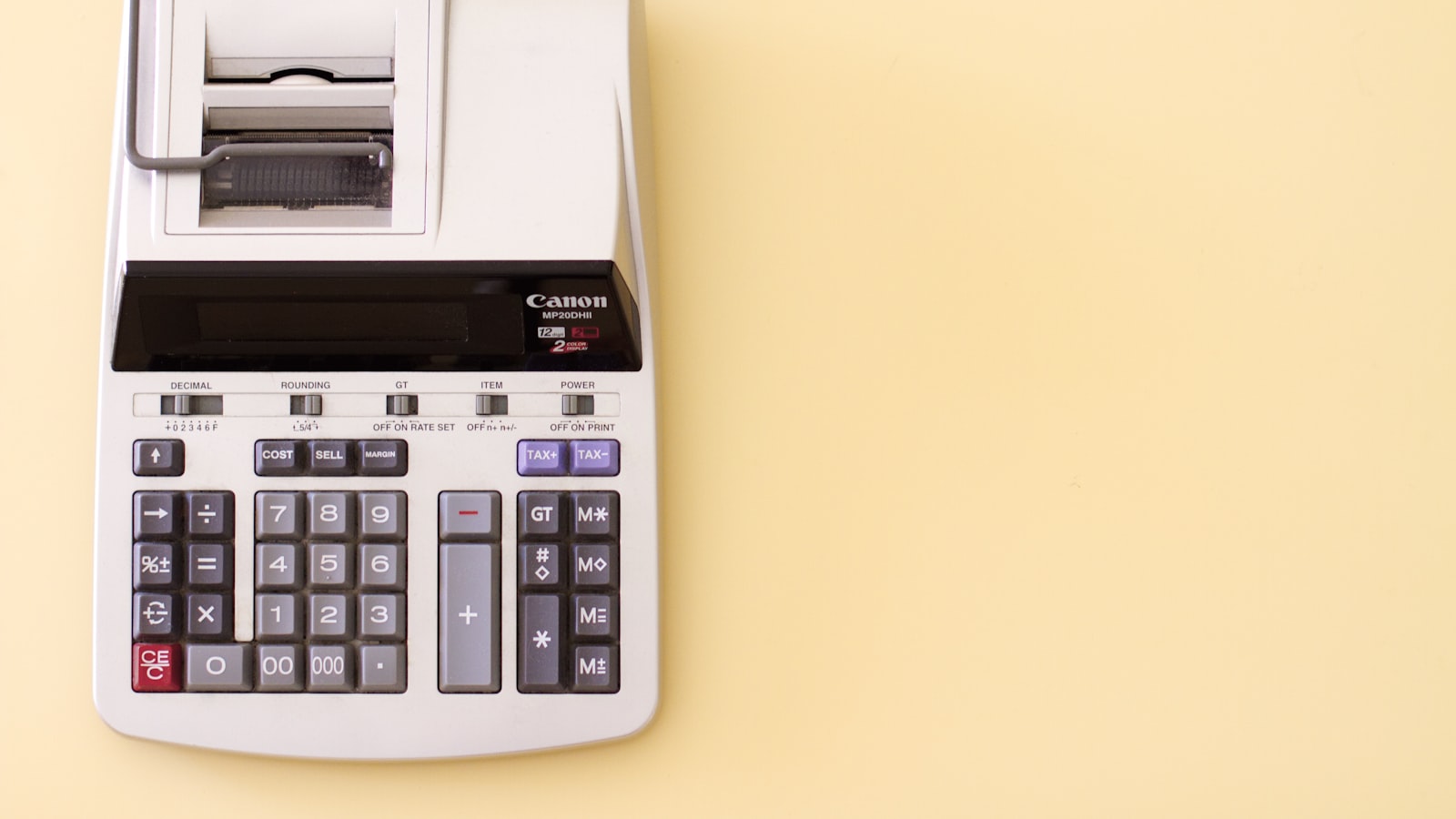 A printing calculator on a yellow background, viewed from above
