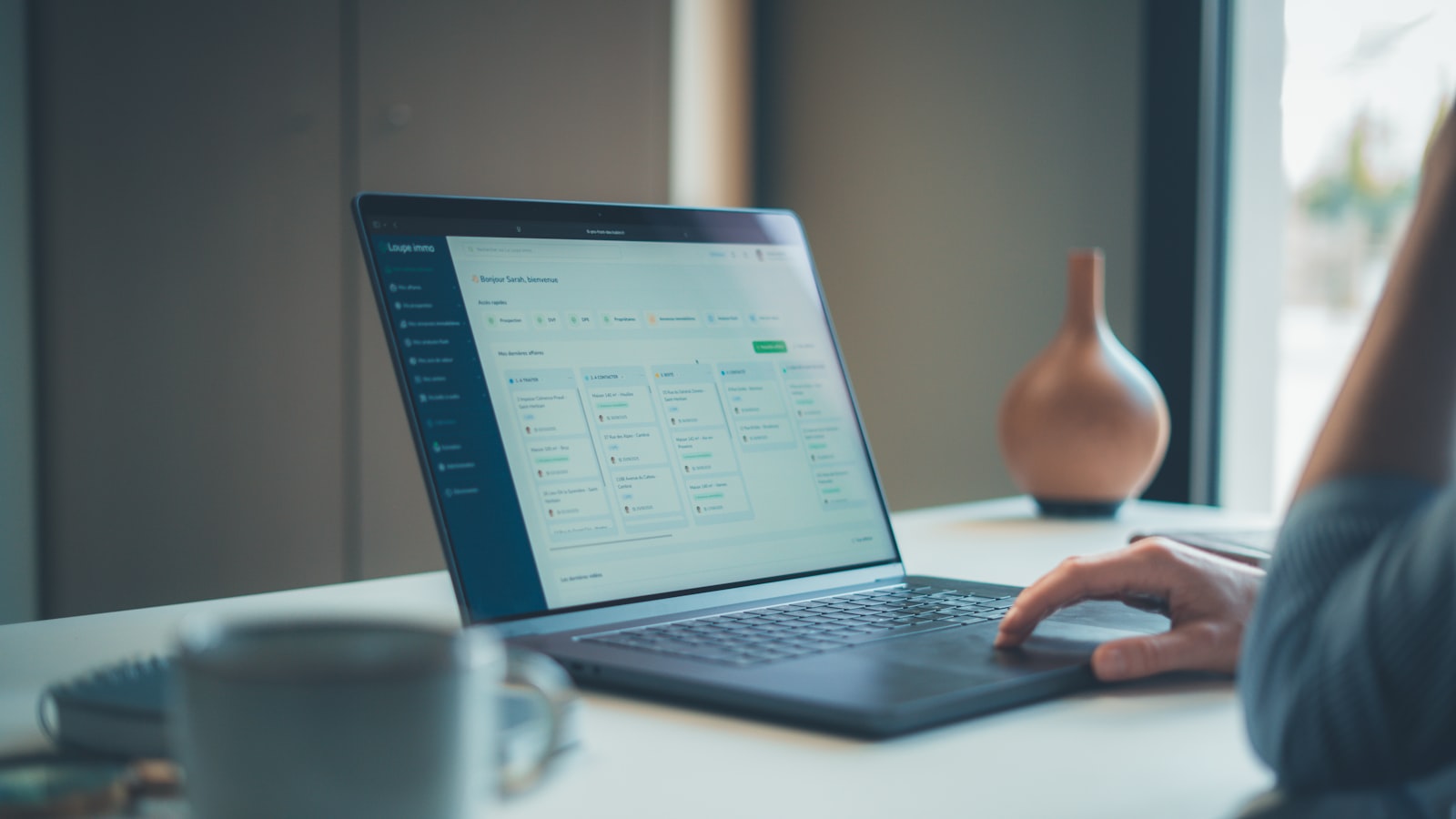 A person uses a laptop on a desk displaying a software dashboard