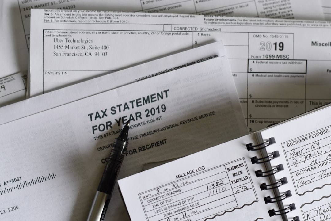 A pen, a mileage log, and a tax statement for the year 2019 are scattered on a surface