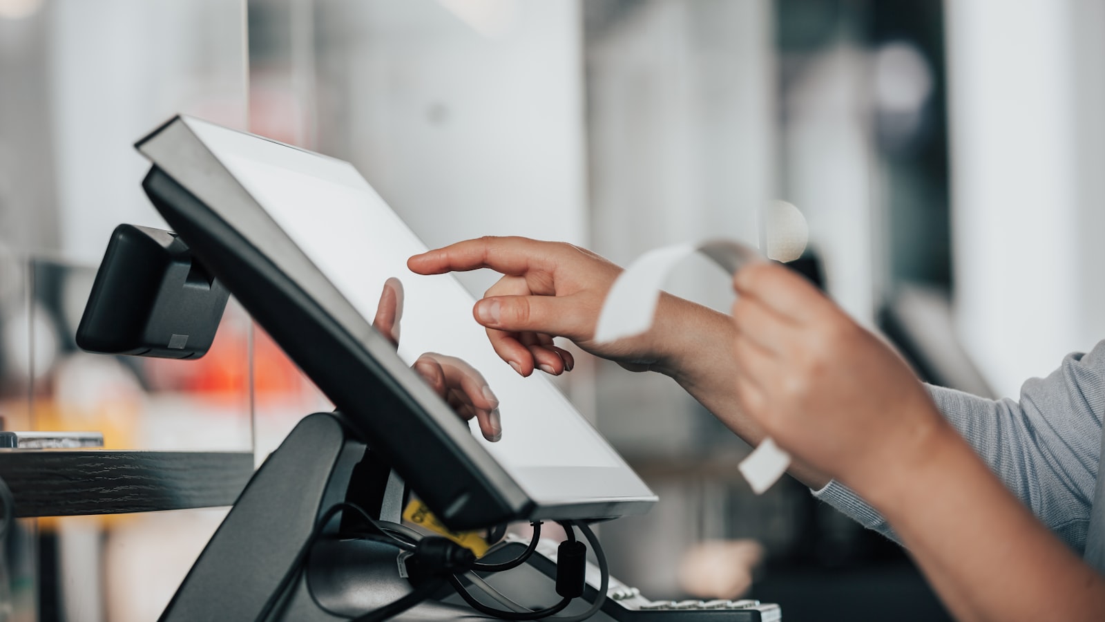 A person’s hands operating a POS terminal and holding a paper receipt