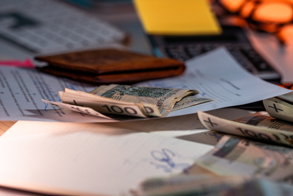 A brown wallet, folded Polish banknotes, and documents on a desk with a calculator