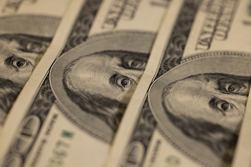 A close-up of multiple US one hundred dollar bills overlapping
