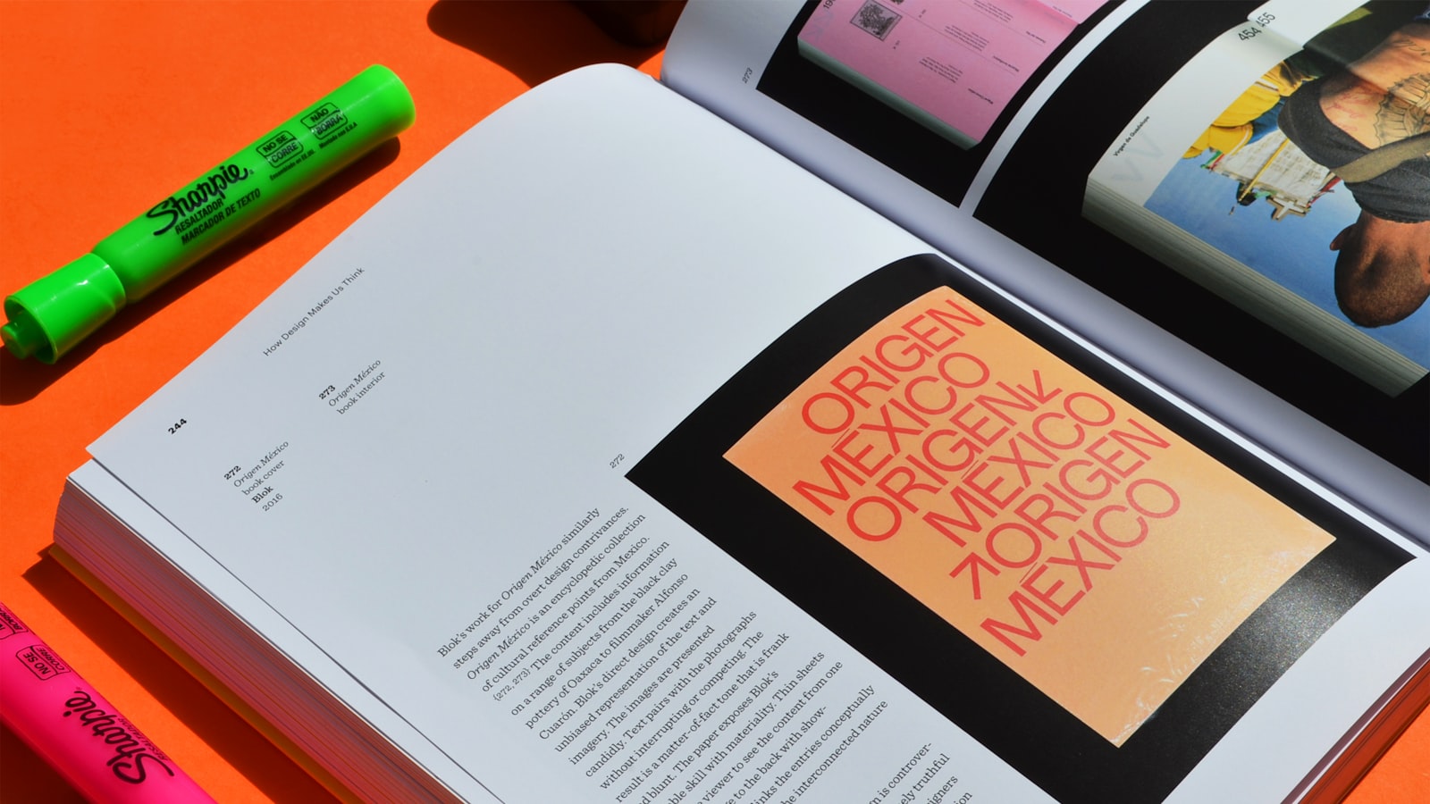 An open book and two highlighters rest on an orange surface