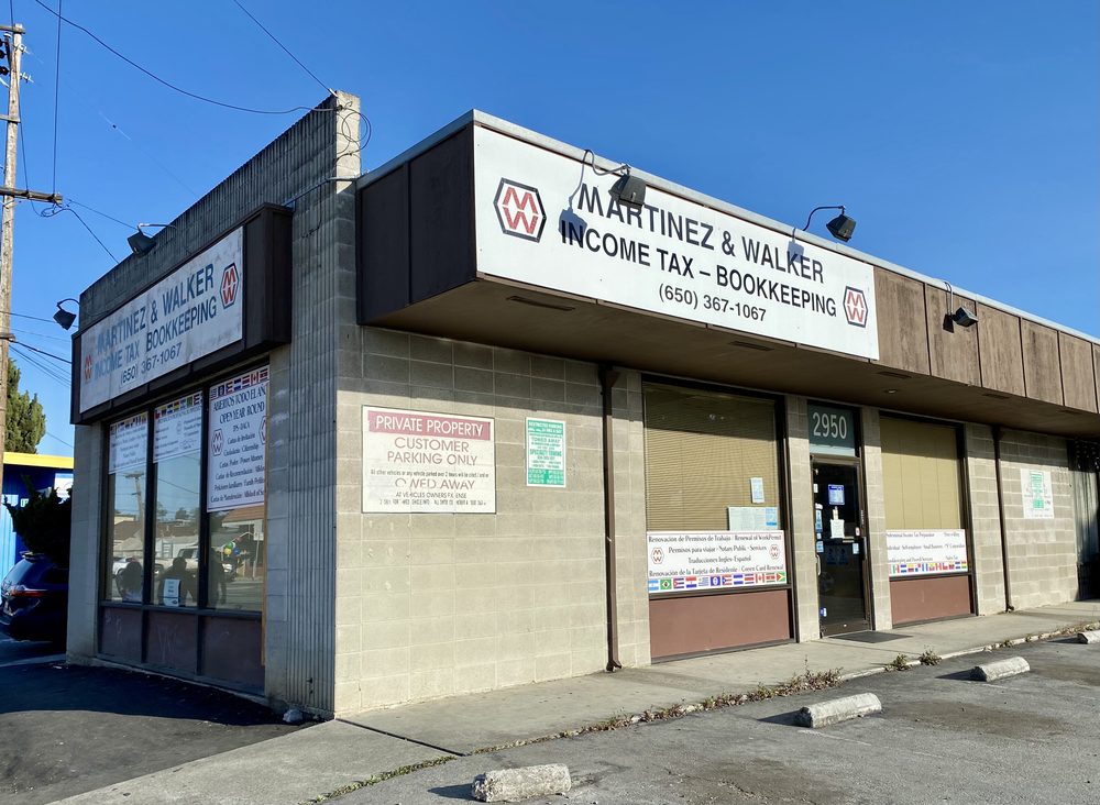 A single-story commercial concrete block building with signage reading "Martinez & Walker Income Tax-Bookkeeping