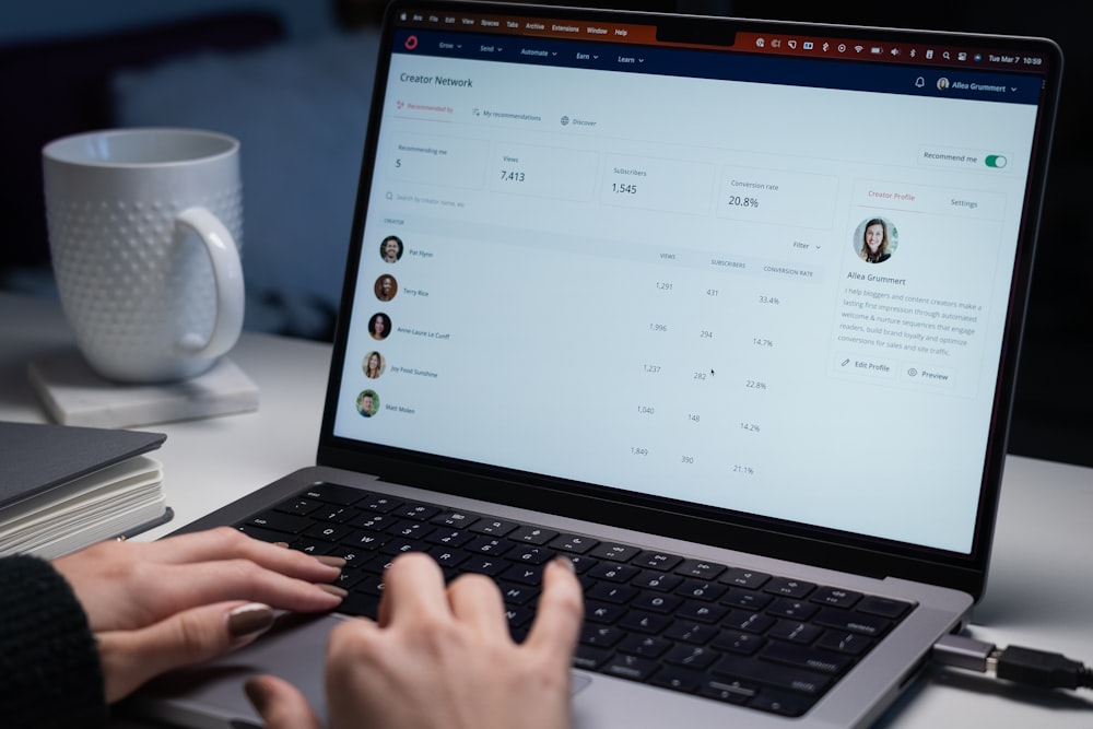 A screenshot on a laptop screen shows a creator network dashboard with user stats and a list of profiles