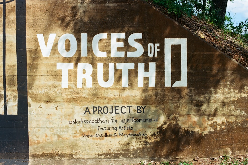 White text reading VOICES OF TRUTH painted on a weathered concrete wall