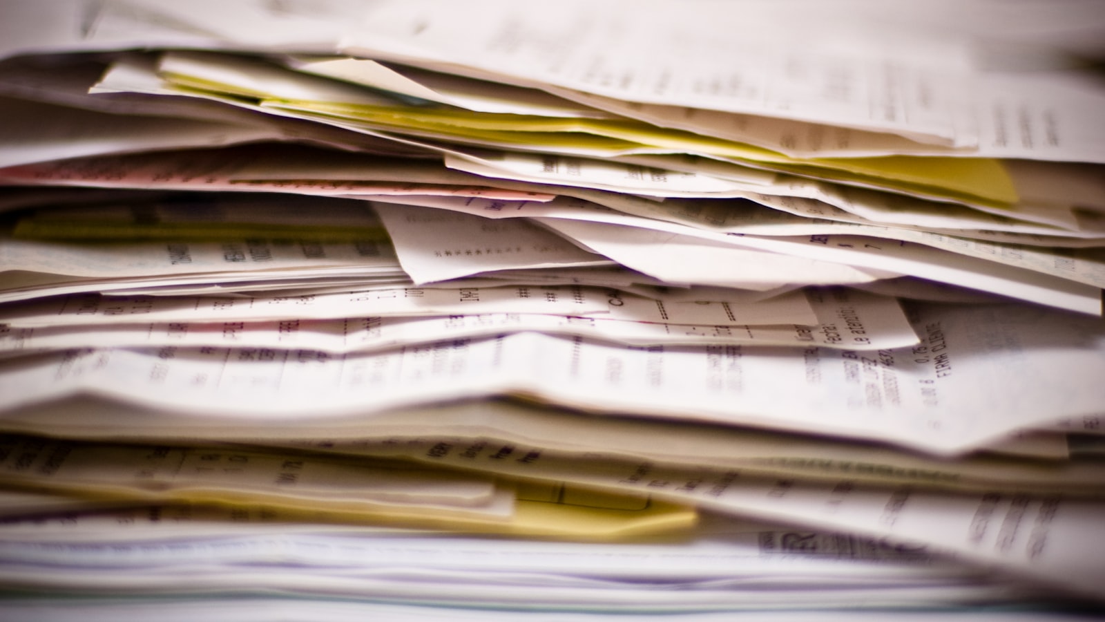 A messy stack of folded receipts and papers fills the frame